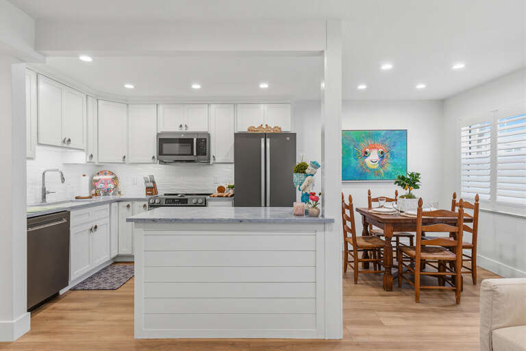 Enjoy a stylish beach stay with this updated kitchen and cozy dining area featuring bright coastal touches, modern appliances, and an open layout perfect for gathering after a day by the beach.