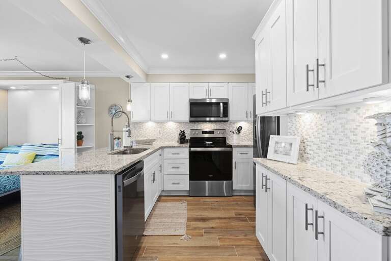 Cook and gather in this beautifully updated beach stay kitchen featuring granite countertops, stainless steel appliances, custom cabinetry, and an open layout designed for easy coastal living.