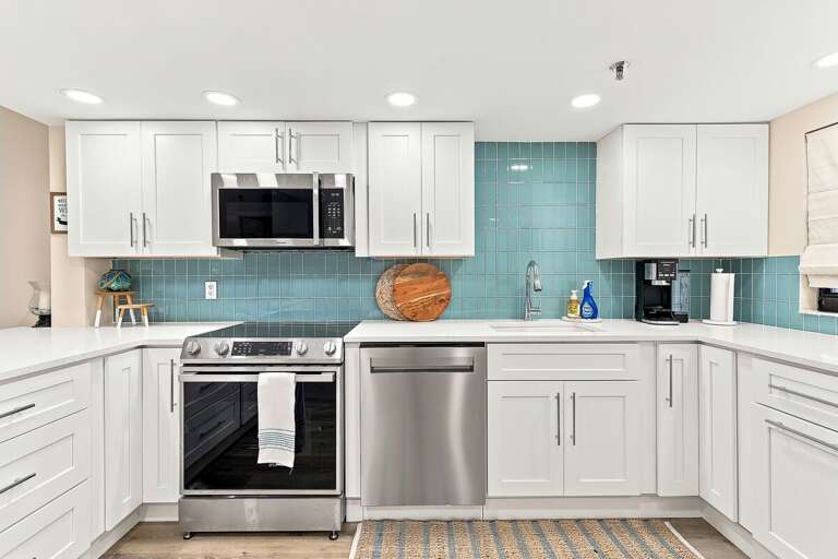 Prepare meals in this bright coastal kitchen featuring stainless steel appliances, quartz