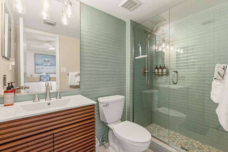 Freshen up after a day at the beach in this stylish bathroom featuring a glass-enclosed walk-in shower, modern vanity, and soothing coastal-inspired finishes for a comfortable beach stay.