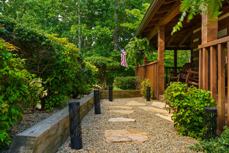 A tidy stone path leads through fresh greenery to your door — the first hint of the sleek, modern retreat waiting inside Dancing Embers.