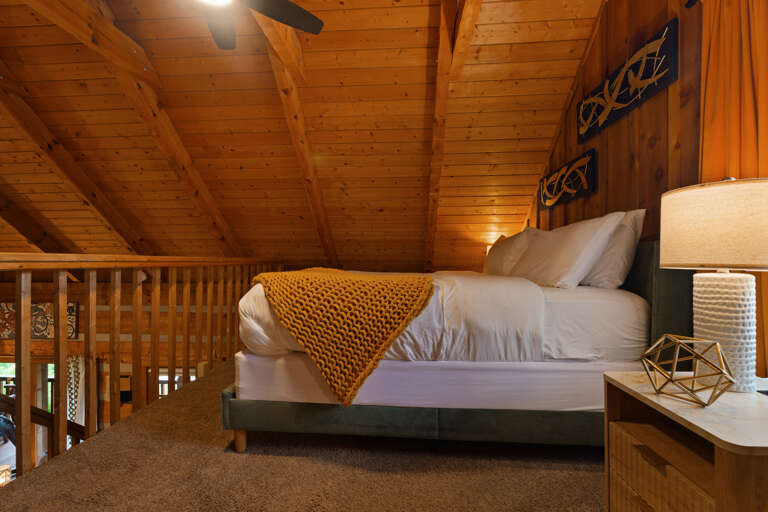 Tucked under the eaves, this stylish loft bedroom offers a peaceful night's rest with modern mountain-cabin flair.