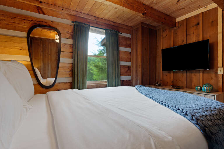 Unwind in style in this comfortable bedroom suite, complete with a mounted TV and calming blue accents at Dancing Embers.