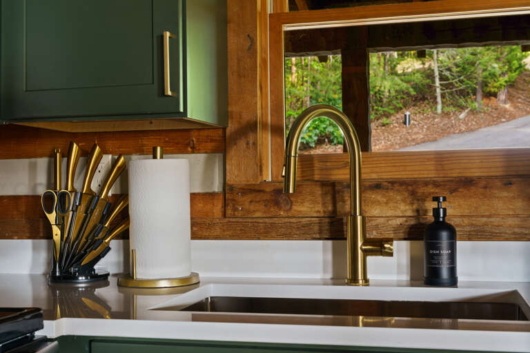 Wash dishes with a view — sleek gold fixtures and forest scenery make even the small moments feel special at Dancing Embers.