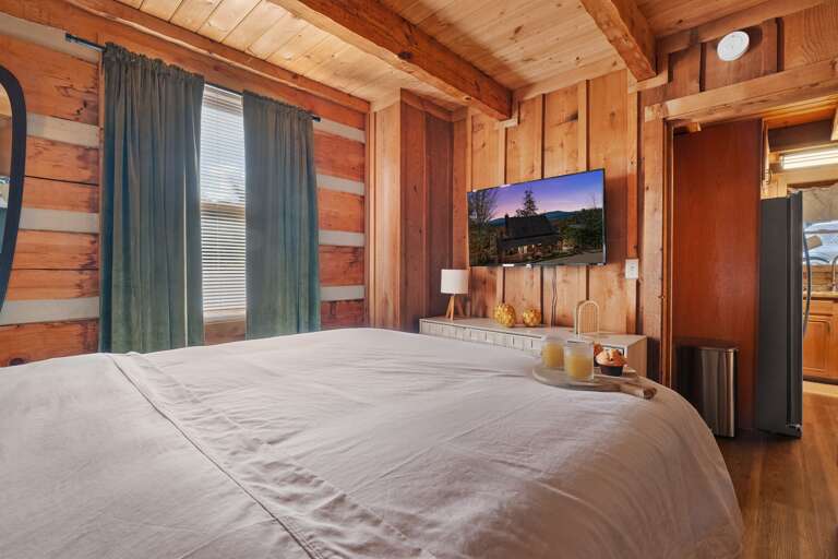 Comfortable bedroom with a plush bed, warm wood finishes, and a TV for relaxing winter nights at Dancing Embers.