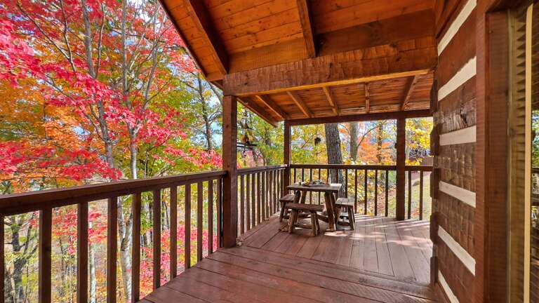 Enjoy peaceful forest views from the covered deck — complete with outdoor dining and rocking chairs for slow Smoky Mountain mornings.