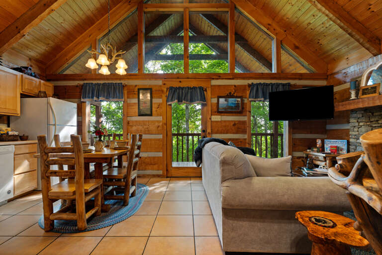 Big windows fill the open living and dining area at Nestled Oaks with natural light and peaceful forest views.