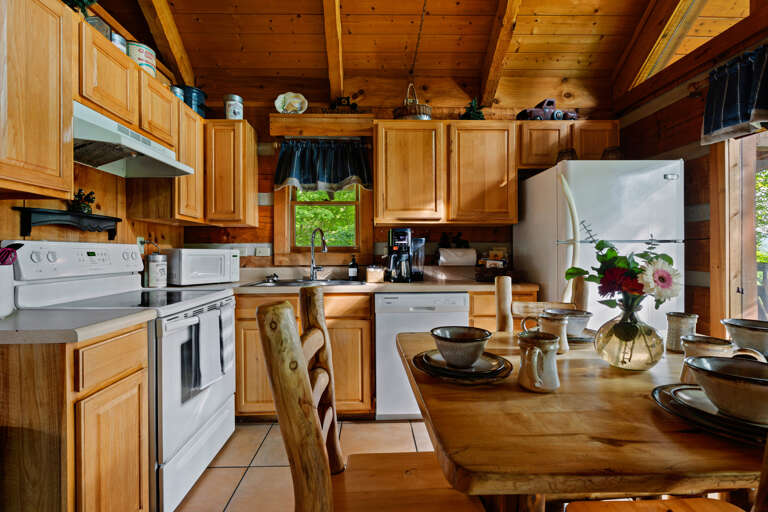 Gather around the rustic dining table at Nestled Oaks for a home-cooked meal surrounded by log cabin charm.