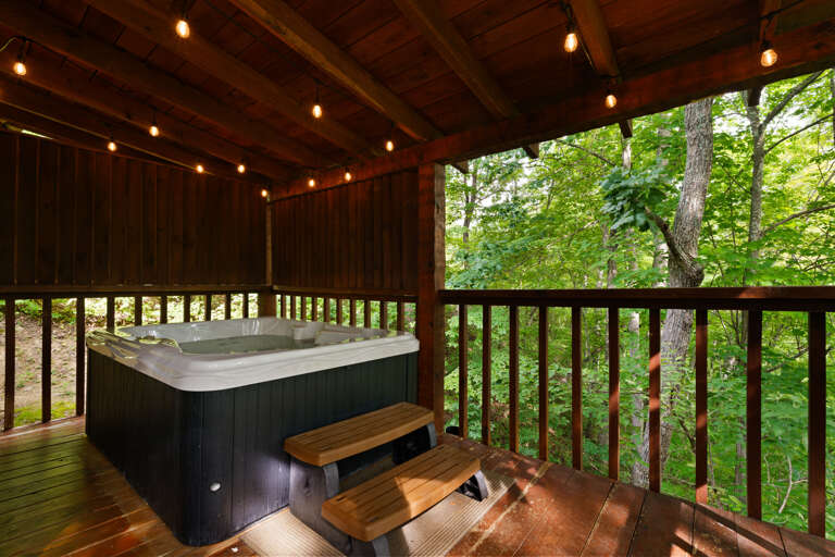 Soak beneath twinkling lights and towering trees — the private hot tub at Nestled Oaks sets the scene for a romantic getaway.