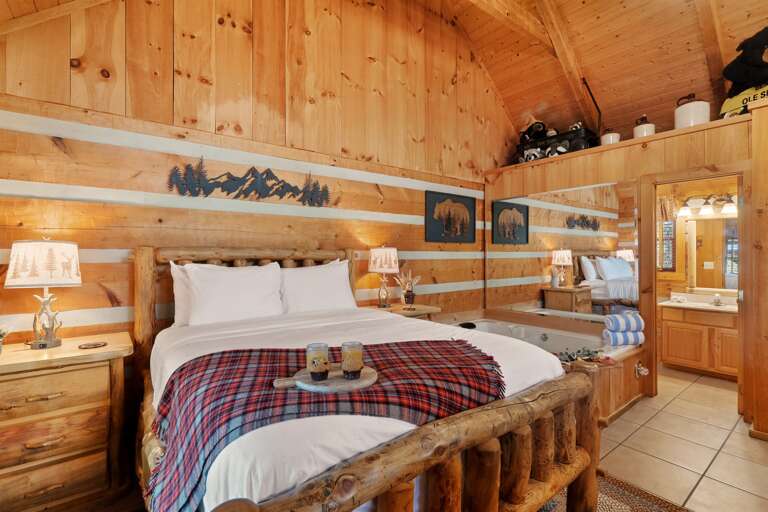 A cozy studio retreat featuring a handcrafted log bed, warm wood interiors, and a private in-suite jetted tub—designed for rest, relaxation, and a quiet Smoky Mountain escape at Nestled Oaks.