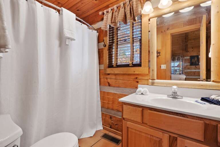 Bright, spotless bathroom with rustic wood accents, natural light, and fresh towels ready for your stay.