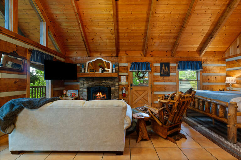 Log furnishings, a warm fireplace, and peaceful wooded views make the living room at Nestled Oaks a true mountain escape.