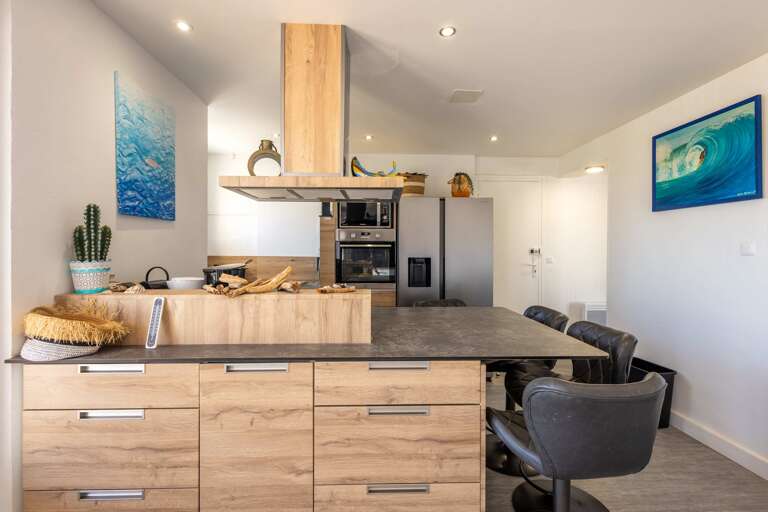 Kitchen With Wooden Cabinets, Bar Stools, Ocean Artwork