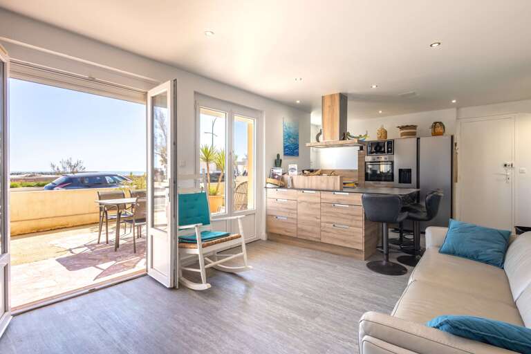 Sunlit Space With Sea View, Open Doors, And Sleek Kitchen