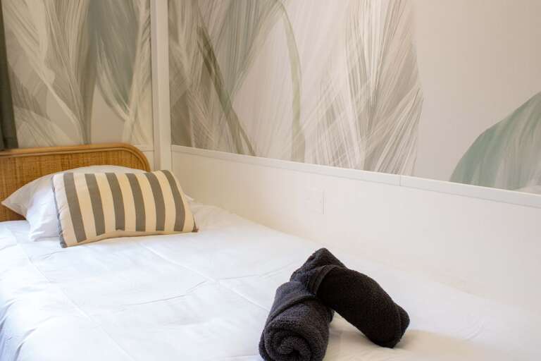 Bed With Striped Pillow, Folded Towels, Abstract Wall Art