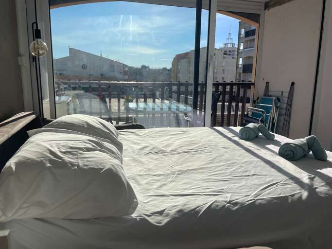 Bed Beside Balcony, Bright Sunlit Scene