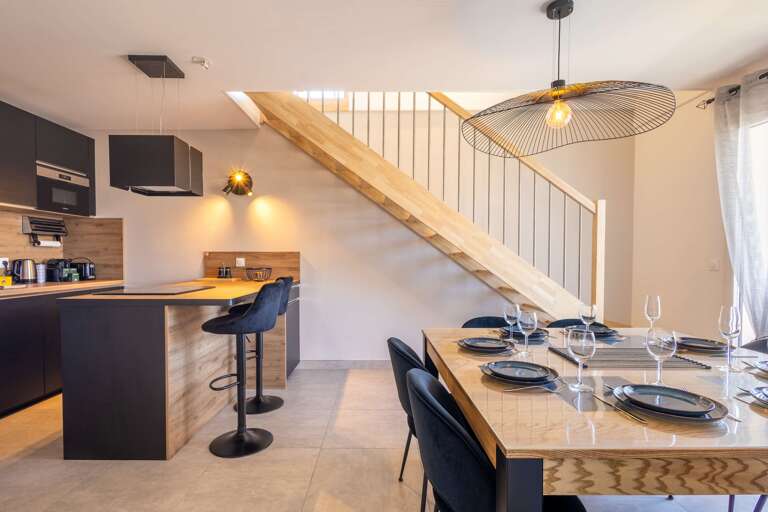 Kitchen And Dining Area With Wooden Staircase And Barstools