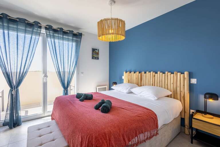 Bed With Bamboo Headboard, Blue Wall, Sheer Curtains, And Hanging Light