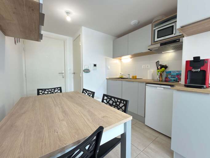 Compact Kitchen With Table, Chairs, Microwave, And Coffee Maker