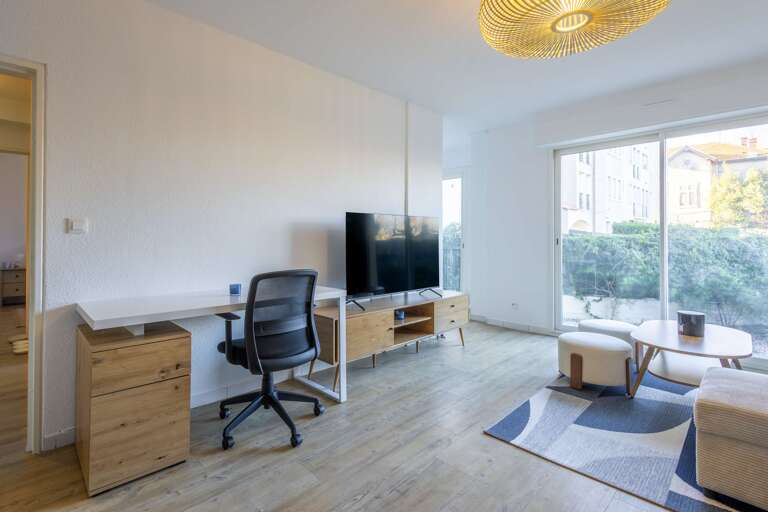 Living Area With Desk, TV, And Sliding Glass Door