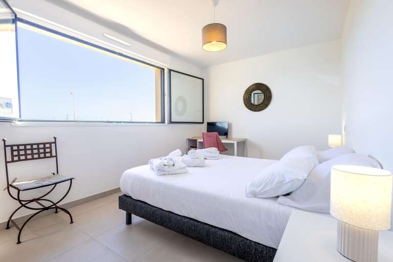 Bright Room With Bed, Chair, Desk, And Large Window