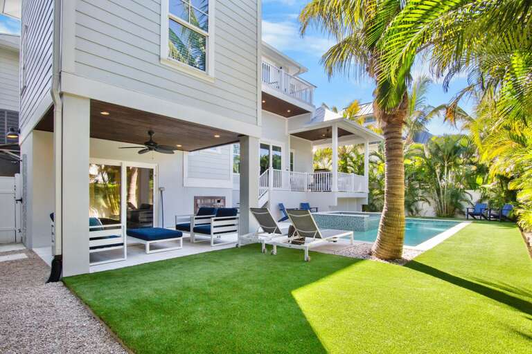 Sparkling pool, lush palm trees, and covered lounge area perfect for outdoor relaxation.