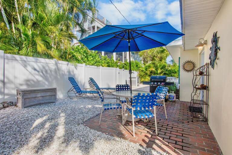 Your private patio features comfortable seating, a BBQ grill, and tropical palm views - perfect for outdoor dining and relaxation in the Florida sunshine.