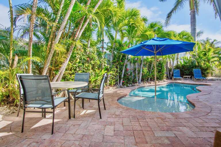 Relax by your private tropical pool surrounded by swaying palm trees, with comfortable poolside seating and shade umbrellas for the perfect vacation retreat.