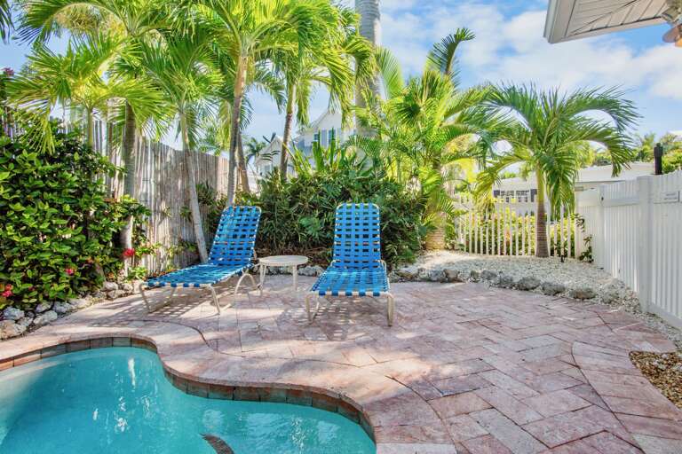 Relax by your private pool surrounded by tropical palms and comfortable lounge chairs on a sunny paver deck.