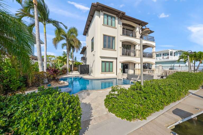 Waterfront villa with pristine pool, tropical palms, and multiple balconies overlooking the canal