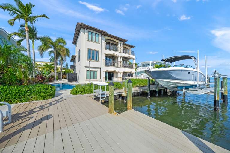 Private dock and boat access, surrounded by tropical palms and sparkling pool.