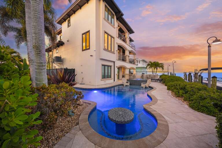 Stunning waterfront villa with elegant pool and breathtaking sunset views over tropical paradise.