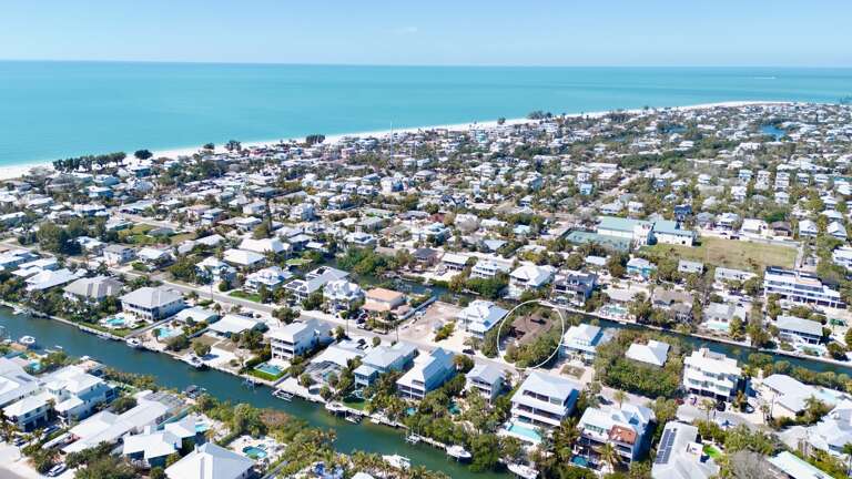 Aerial view of a coastal neighborhood with waterfront homes, canals, and beach access in a picturesque seaside community.