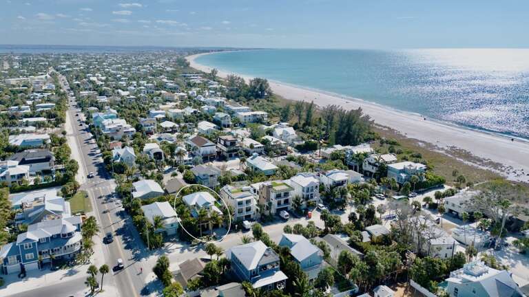 Beachfront community with pristine white sand beach and turquoise waters stretching to the horizon.
