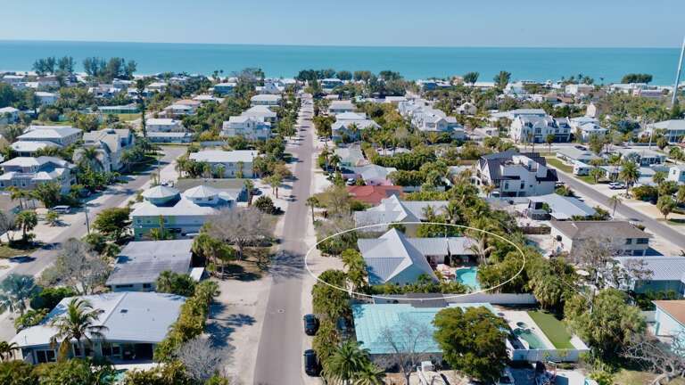 Coastal neighborhood with tropical homes and swimming pools near pristine beachfront, offering a serene island setting for your getaway.