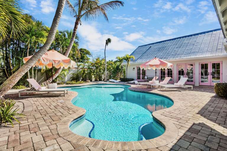 Private tropical oasis with pool surrounded by swaying palms and comfortable loungers