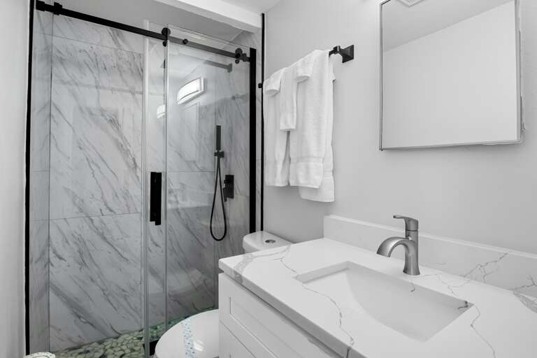Bright bathroom with walk-in shower and fresh towels provided.