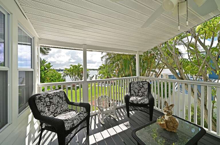 Relax in your private covered balcony with comfortable wicker seating and peaceful water views through tropical foliage.