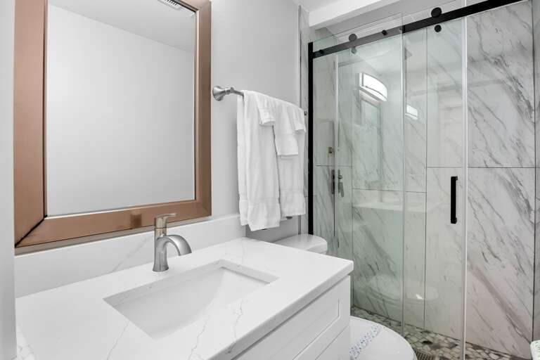 Bright bathroom with walk-in shower and fresh towels provided.