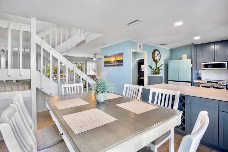 Your open-concept kitchen and dining space features modern blue cabinetry, stainless appliances, and a welcoming dining table for memorable meals.
