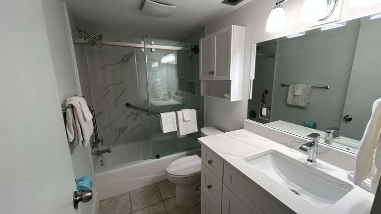 Step into your modern bathroom featuring a sleek glass shower, marble-style walls, and pristine white vanity with premium fixtures.