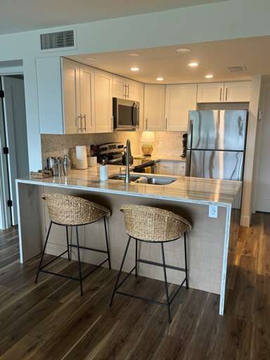 Cook your favorite meals in this modern kitchen featuring stainless steel appliances, elegant white cabinetry, and a convenient breakfast bar for casual dining.