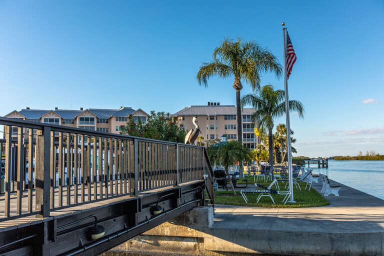 Waterfront property featuring private dock, palm trees, and peaceful bay views in a scenic coastal setting.