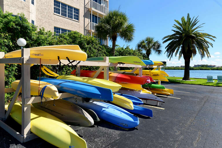 Colorful kayaks await your waterfront adventure, with tropical palms and scenic lake views creating the perfect vacation backdrop.