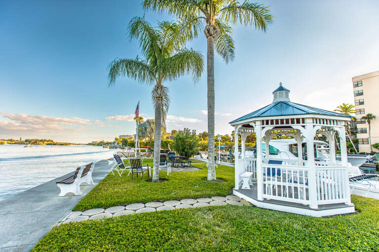 Waterfront property featuring a charming gazebo, palm-lined lawn, and direct access to scenic bay views with boat docks.