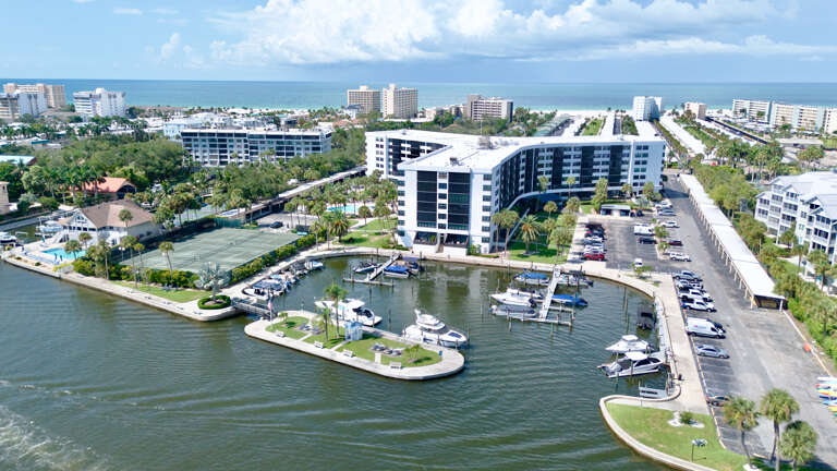 Waterfront community featuring marina access, resort-style buildings, and tropical landscaping near pristine coastal waters.