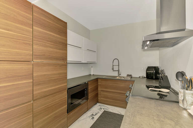 Your sleek modern kitchen features warm wood cabinetry and premium appliances, perfect for creating memorable meals during your stay.