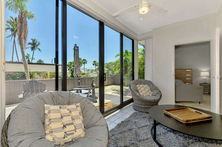 Unwind in your stylish living space where floor-to-ceiling windows frame tropical palms, creating a seamless indoor-outdoor flow.