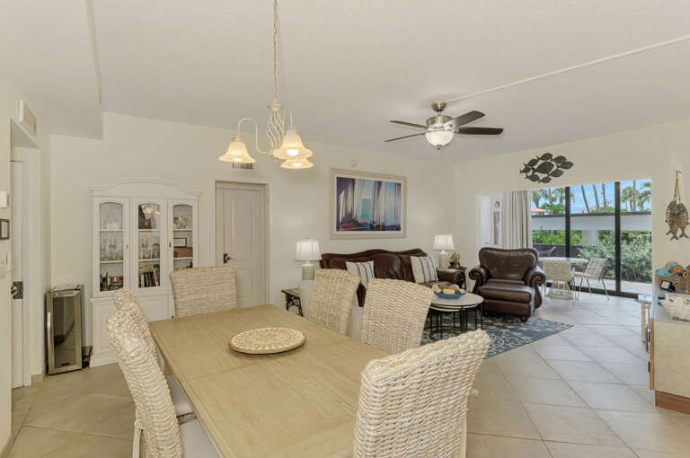 Step into your bright, open-concept living space where coastal charm meets comfort with wicker dining chairs and leather seating.