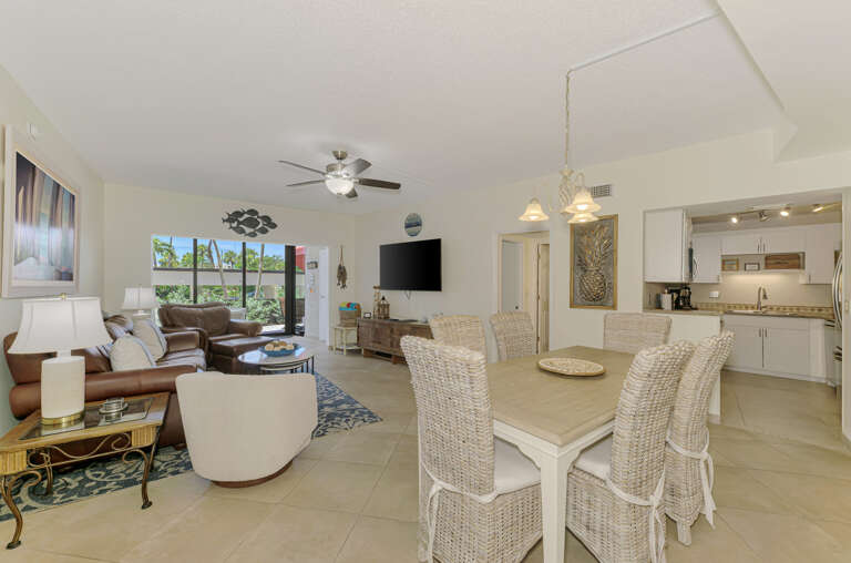 Your open-concept living space seamlessly blends comfort and coastal style, with wicker dining chairs and leather sofas perfect for relaxing.